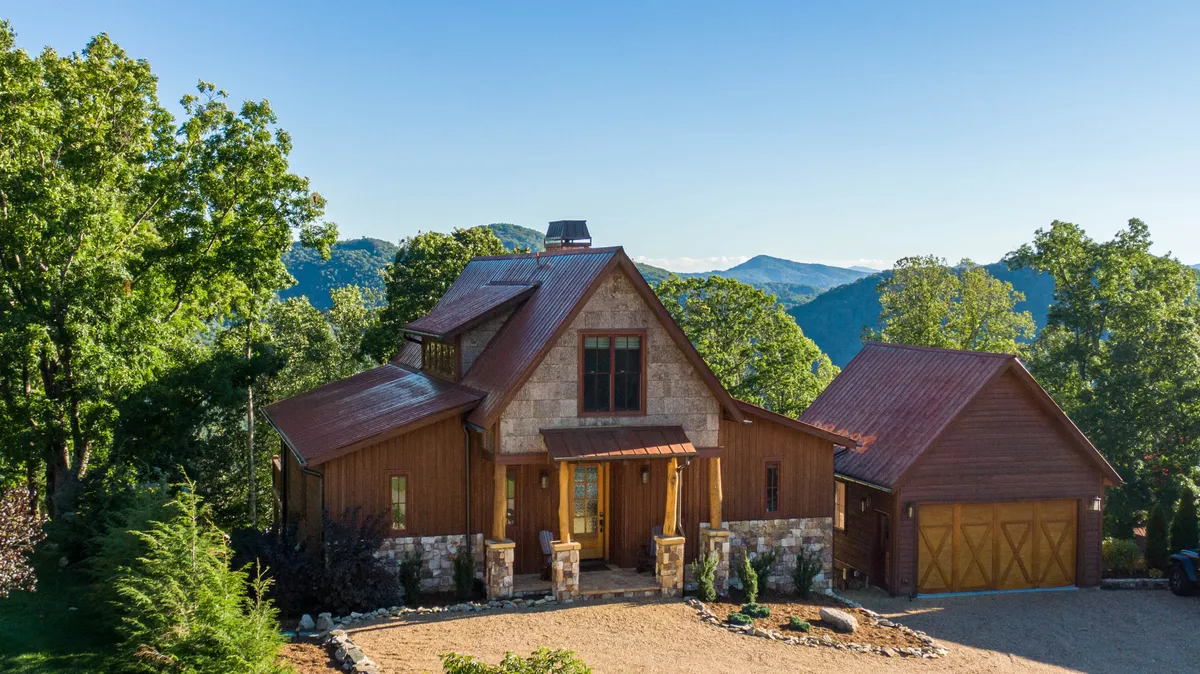 This image showcases the home's striking stone and wood facade, a welcoming front porch perfect for relaxation, and a distinctive roofline that highlights its mountain charm. The porch invites guests to gather, take in sweeping mountain views, and enjoy the peaceful natural surroundings of Eagles Nest.